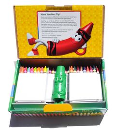 an open box with crayons in it and a green plastic container filled with markers