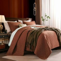 a bed with brown and white comforters in a bedroom next to a lamp on a table