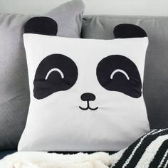 a panda pillow sitting on top of a couch next to a white and black blanket