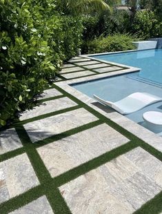 an empty swimming pool surrounded by greenery and lawn furniture in the middle of it