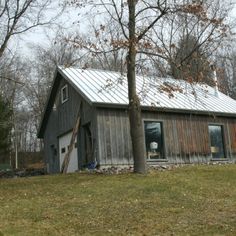 an old barn sits in the middle of a grassy area with trees and grass around it