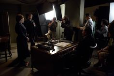 a group of people standing around a table in front of a camera and recording equipment