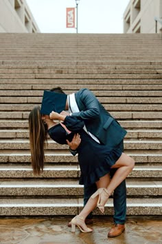 a man and woman kissing in front of stairs with their graduation cap on top of them