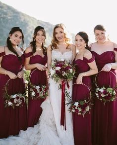 a group of women standing next to each other wearing dresses and holding bouquets in their hands