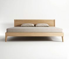 a bed with two pillows on top of it and a wooden headboard in the middle