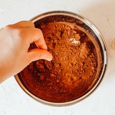 a person is mixing some food in a bowl on the table with their hand over it