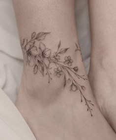 a woman's foot with flowers and leaves tattooed on the side of her leg