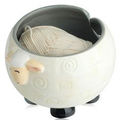 a yarn ball in a ceramic bowl with sheep head on the bottom and white wool inside