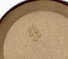 a brown bowl filled with sand on top of a white table