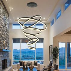 a modern living room with stone fireplace and large window overlooking the mountains is lit by an elegant chandelier