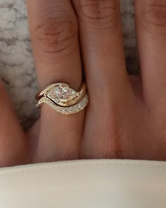 a woman's hand with two gold rings on top of her finger and the ring has three diamonds in it