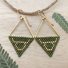 the triangle earrings are made from green seed beads and gold plated brass wire, with an arrow shaped design