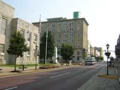 an empty street in front of a large building with trees on both sides and a truck driving down the road