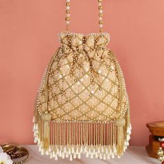 a gold purse with beads and tassels hanging from the side on a table