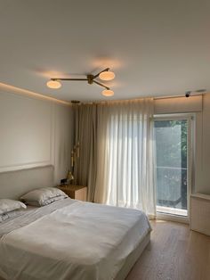 a bedroom with a large bed sitting next to a window covered in white drapes