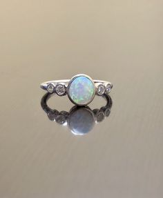 an opal and diamond ring sits on a table