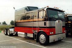 a red and silver semi truck parked in a parking lot next to another semi truck