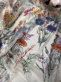 the fabric has flowers on it and is white with multicolored daintys