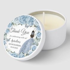 a candle that is sitting in front of a white bowl with blue roses on it