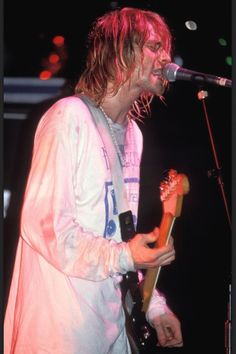 a man standing in front of a microphone holding a guitar