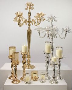 a table topped with lots of different types of glass candlesticks and candle holders