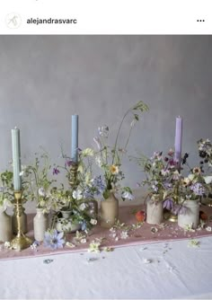 a table topped with vases filled with different types of flowers and candles next to each other