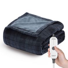 a person holding a remote control in front of a blanket on top of a bed