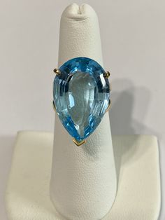 Stunning statement 14k yellow gold genuine blue topaz ring! This gorgeous ring contains a faceted pear cut genuine blue Topaz gemstone that weighs approximately 27.32 carats! The pear shaped gem is secured by 3 thick prongs. Incredible piece of fine jewelry featuring December birthstone! ERA - Modern, Estate METAL / MATERIAL - 14k yellow gold, 1 genuine Blue Topaz (approx. 27.32 cts) MARKINGS / HISTORY - Inside of ring is marked 14k CONDITION - Great vintage condition. SIZE / MEASUREMENTS - Size Blue Topaz Teardrop Ring, Blue Topaz Teardrop Ring Fine Jewelry, Fine Blue Topaz Ring Pear-shaped, Formal Blue Pear-shaped Topaz Ring, Luxury Yellow Gold Pear-shaped Topaz Ring, Fine Jewelry Blue Pear-shaped Topaz Ring, Pear-shaped Blue Topaz Yellow Gold Jewelry, Fine Jewelry Pear-shaped Blue Topaz, Pear-shaped Blue Topaz Jewelry For Gifts