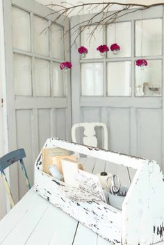 a white table topped with an old wooden box filled with items next to a window