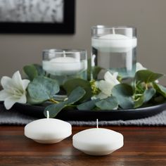 two white candles sitting on top of a wooden table