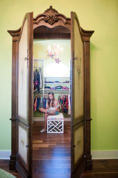 a woman is sitting on the floor in front of a mirror with clothes hanging up