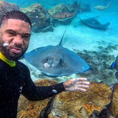 a man in a wet suit standing next to a stingfish