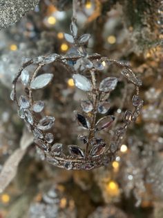 a christmas ornament hanging from the side of a tree with lights in the background