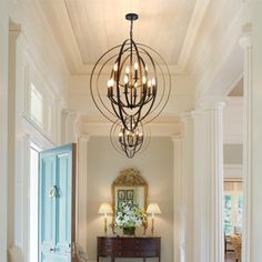 a hallway with a chandelier hanging from it's ceiling next to a doorway