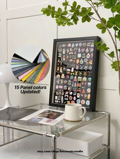 a glass table topped with a coffee cup next to a plant and a poster on the wall