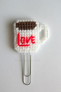 a crocheted cup with the word love on it is attached to a clip