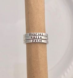 "STERLING SILVER NAME RINGS This listing features beautiful sterling silver rings that are hand stamped with your choice of name or saying as well as spacer ring options. This listing is for ONE ring. The pictures show multiple rings stacked to show the effect of the rings together. The rings are solid sterling silver. Each name ring measures just over 3mm wide. The bead spacer ring measures 2mm wide and the stardust spacer ring measures 1.5mm wide. The personalized rings will be hand stamped wi Adjustable Stamped 925 Midi Rings For Anniversary, Promise Ring Stackable Adjustable Stamped 925 Rings, Personalized Silver Ring With Meaningful Style, Meaningful Silver Stackable Jewelry, Adjustable Stamped Rings For Anniversary, Sterling Silver Stackable Engraved Toe Ring, Adjustable Silver Rings With Meaningful Style, Adjustable Silver Meaningful Rings, Adjustable Sterling Silver Stackable Rings For Anniversary