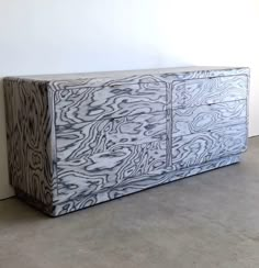 a large white and black cabinet sitting on top of a cement floor next to a wall