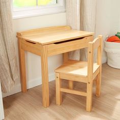 a small wooden table and chair in front of a window with curtains on the windowsill