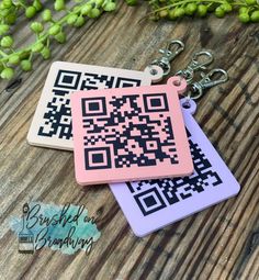 two keychains with qr code on them sitting on a wooden table next to grapes