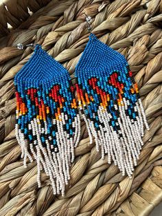 two pairs of beaded earrings sitting on top of a woven basket