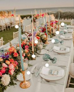 a long table is set up with flowers and candles for an outdoor wedding reception at the beach