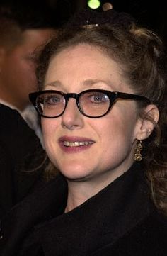 a woman wearing glasses is smiling for the camera