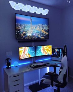 two computer monitors sitting on top of a desk in front of a large screen tv