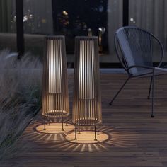 two tall metal vases sitting on top of a wooden floor next to a chair