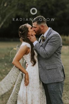 a bride and groom kissing in front of a fence