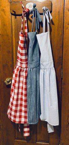 three aprons hanging on a door hanger