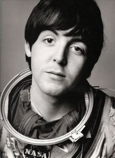 a black and white photo of a young man in an astronaut's suit looking at the camera