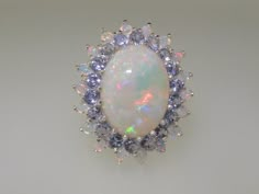 *This Large floral cluster design is handmade from 375 9K White Gold and handset with Natural Semi-precious Opals and Tanzanites.This is an impressive cluster set with a center 16x12mm (0.64"x0.48" inches) Stunning Natural Australian Opal complimented by eighteen 2.75mm (0.11" inches) Natural Tanzanites and eighteen 2.25mm (0.09" inches) Natural Australian Opals. This is a real beauty of a dress ring! The Gemstones are Natural and Ethically Sourced.PLEASE INCLUDE A TELEPHONE NUMBER WITH YOUR PAY Opal And Sapphire Ring, Rings Opal, Flower Halo, English Vintage, Cluster Design, Precious Opal, Dress Ring, Natural Tanzanite, Telephone Number