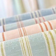 three different colored striped fabrics with water drops on them, one is blue and the other is pink